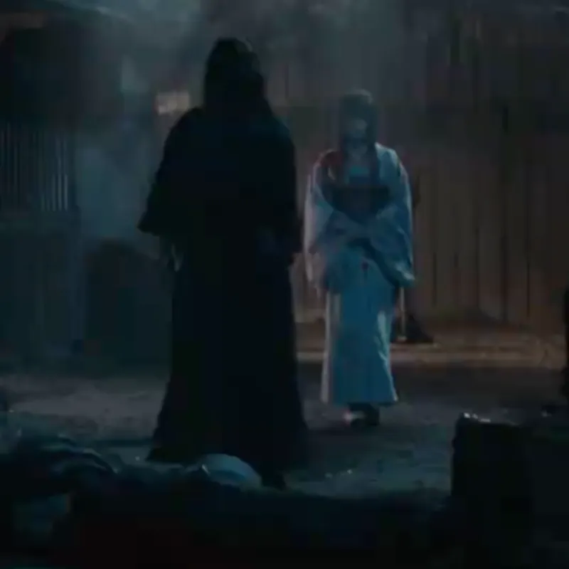 Kenshin standing before Lady Tomoe, right after splattering his adversary's blood on her. Kenshin is wearing a black kimono and lady Tomoe is wearing a white kimono which is stained red at the shoulder level with blood. This is taking place outside of the inn, where it's dark, and gloomy. There's only a faint light in the background coming from an amber colored lamp, along with the white shimmering light brought upon by the moon.