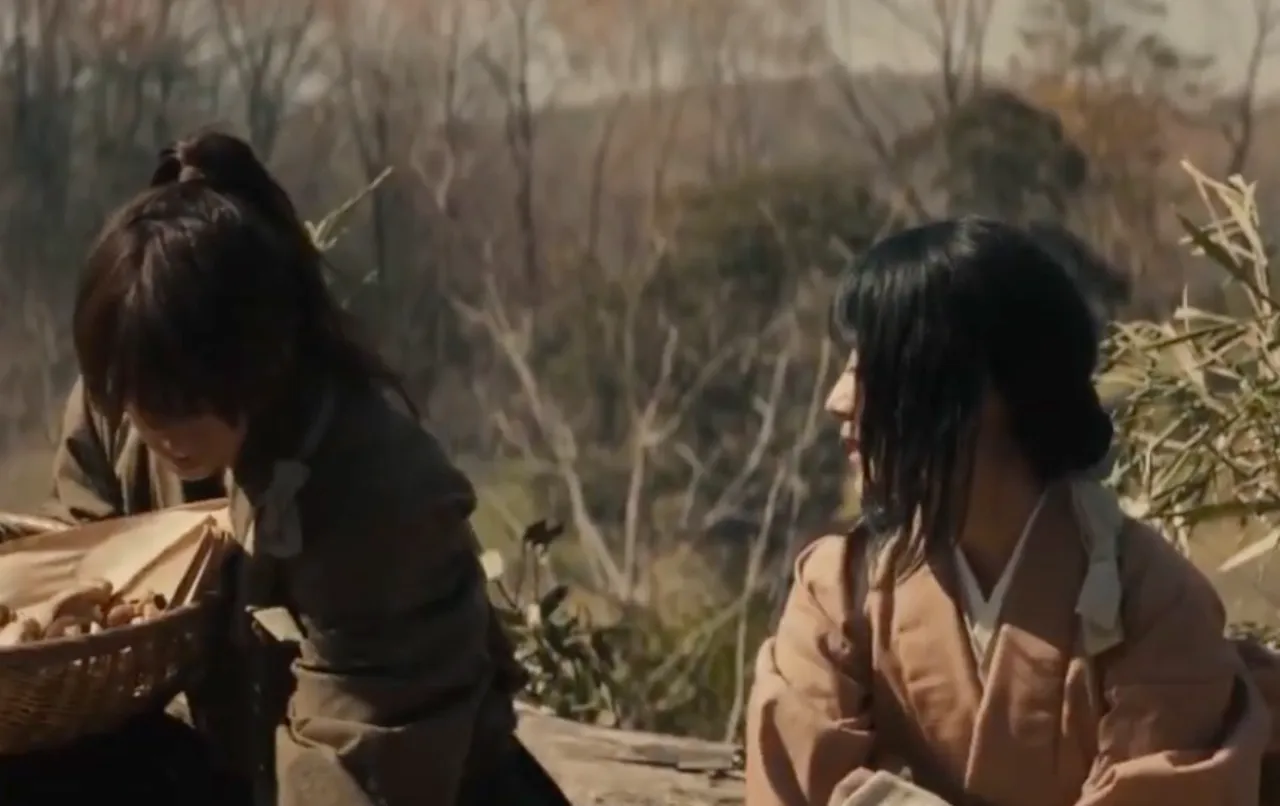 In this image, Lady Tomoe and Kenshin are collecting vegetables from their farm. The scene is sunlit, accompanied by the dry nature of the land during that season.