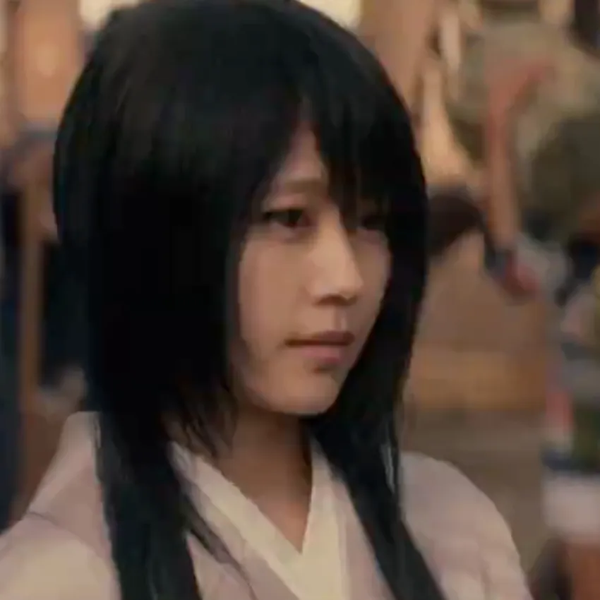 In this scene, Kenshin is staring into a crowd of people. Lady Tomoe is staring at the crowd as well, while standing behind Kenshin. Lady Tomoe is only visible in this shot, she's wearing a light pink garment with a white lapel.